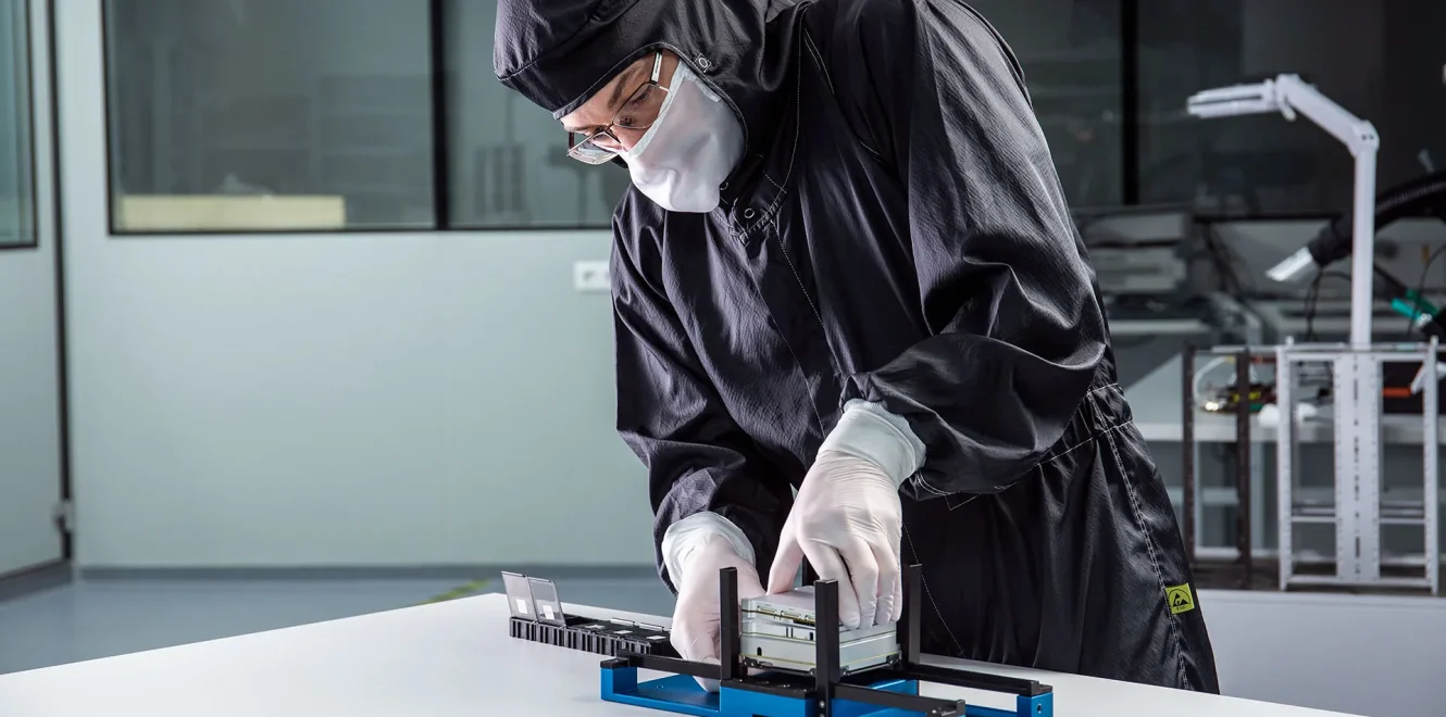 A mid-shot of a technician in a clean room production facility assembling the EnduroSat 1U CubeSat nanosatellite.
