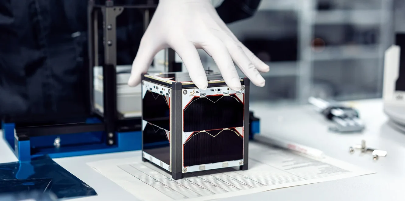 A side view of a technician assembling the EnduroSat 1U CubeSat nanosatellite in a clean room production facility.