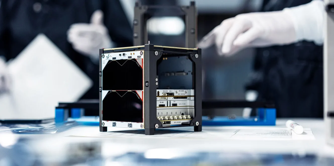 A side view of the EnduroSat 1U CubeSat satellite bus being assembled in a cleanroom production facility, showing its modular design and 1U CubeSat Solar Panels.